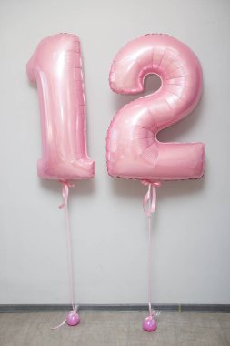 Beyaz arkaplanda 12 numaralı pembe balonlar.