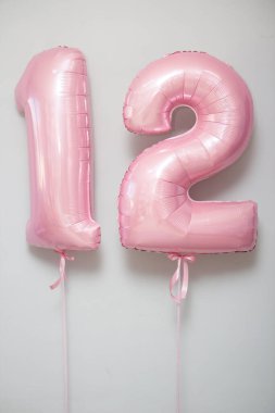 Beyaz arkaplanda 12 numaralı pembe balonlar.
