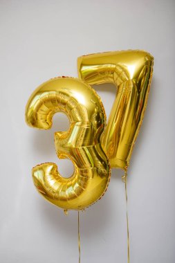Beyaz zemin üzerinde 37 adet altın rengi balon