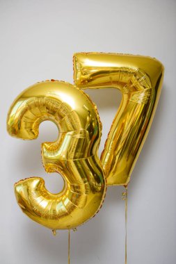 Beyaz zemin üzerinde 37 adet altın rengi balon