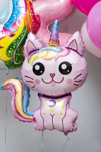 Beyaz arka planda pembe kedi şeklinde tek boynuzlu at şeklinde balon.