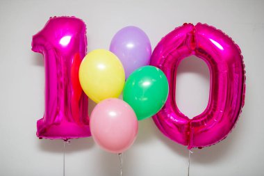 Pembe 10 numaralı balonlar ve beyaz arka planda parlak helyum balonları.