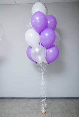 Şeffaf bir balon, mor tüyleri ve bir sürü helyum balonu olan, 