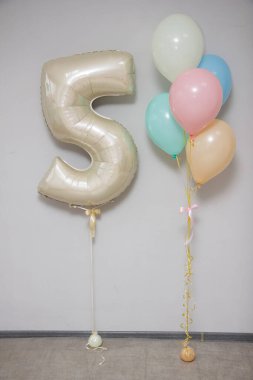 Folyo bej 5 numaralı balon ve bir sürü narin helyum balonu. Bir kızın doğum günü için süslemeler.