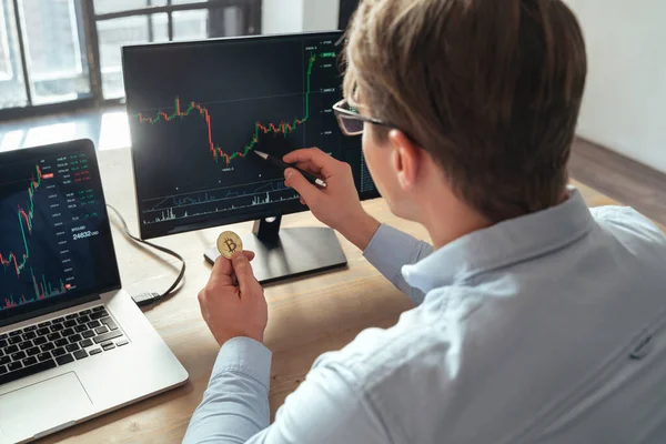 İşadamı yatırımcı elinde altın bitcoin tutuyor veya kripto para jetonları satıyor, hisse senedi piyasası ve yatırım risklerini internette analiz ediyor