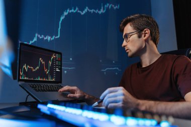 Finansal kripto uzmanı. Ev bilgisayarında gece geç saatlere kadar çalışıyor. Şamdan grafiğini analiz ediyor, monitör ekranına bakıyor.