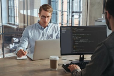 Two IT specialists co-working at office, working on new product, analyzing data, programming new software