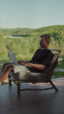 Genç bir erkek serbest yazar, tahta bir sandalyeye oturmuş, doğayla çevrili, huzurlu bir açık hava ortamında çalışırken dizüstü bilgisayarında daktilo yazıyor. İş-yaşam dengesi