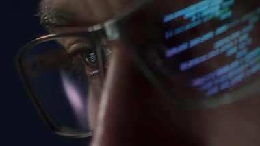 Gözlük, siber güvenlik, kodlama ve yazılım geliştirmeyi sembolize eden, bilgisayar kodlu bir göz aşırı yakın plan.. 