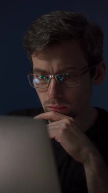 Borsa ya da kripto para birimi şeması olan gözlük takan genç bir tüccar lenslerine yansıdı. Dizüstü bilgisayarındaki kripto para artışına bakan yatırımcı gülümsüyor.. 