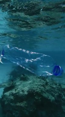 Denizde yüzen bir plastik şişe. Su altı kirliliği deniz yaşamını tehlikeye atıyor ve su ortamının dengesini bozuyor. Dikey video