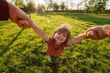 Mutlu bir çocuğun portresi, ailesiyle el ele tutuşup, gün batımında parkta eğleniyor. Kaygısız mutlu bir çocukluk.. 