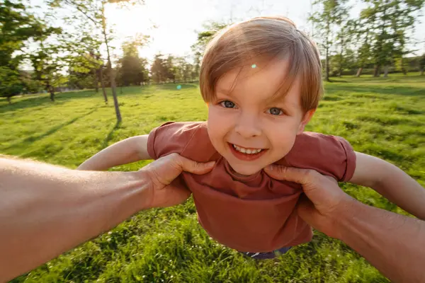 Bir babanın heyecanlı küçük oğlunu gün batımında parkta daireler çizerken ilk bakışı. Kaygısız aile zamanlarının tadını çıkarıyor..