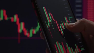 Akıllı bir telefonla borsa şamdan grafiği ile el ele etkileşimi ticareti, yatırımı veya finansal analizi gösterir. 