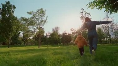 Bir anne ve oğul güneşli bir parkta uçaklar gibi kollarını açıp özgürlüğün ve eğlencenin tadını çıkararak, doğada birlikte oynayarak neşeyle koşuyorlar. Yavaş çekim