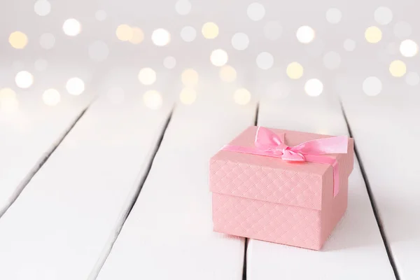 Romantic festive background with present and pink present on white table with lights bokeh