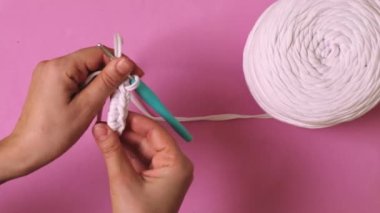 Kadın elinin pembe arka planda kurdele ipliğiyle tığ işi yapması. Yüksek kalite 4k görüntü