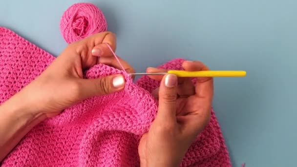 女性の手のトップビューは 青の背景にピンクの綿の糸でクロッキー — ストック動画