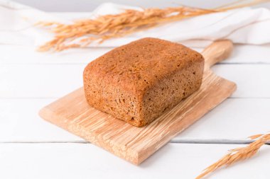 Ev yapımı ekşi ekmek somunu beyaz ahşap arka plan.