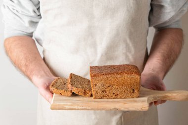 Elleri ahşap tahtanın üzerinde ev yapımı ekşi ekmek tutuyor.