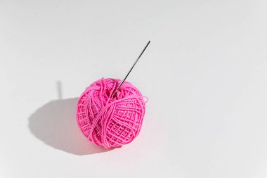 Ball of pink yarn with crochet hook on light background, copy space clipart