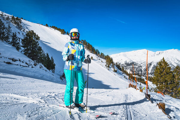 Портрет женщины-лыжницы с лыжами, смотрящей в камеру со склонами позади, Пиренеи. Зимний отдых на лыжах в Эль-Тартере, Грандвалира-Андорра