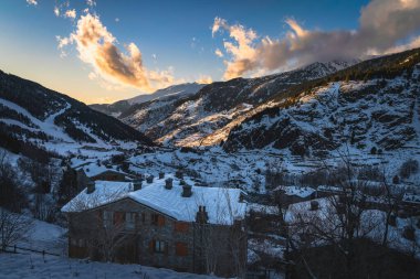 Sunset at El Tarter village with clouds and mountains still illuminated by sunlight and valley in deep shadow. Ski winter holidays, Andorra, Pyrenees