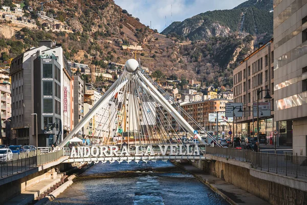 stock image Andorra la Vella, Jan 2020 Pont de Paris bridge crossing Gran Valira river. Hotels and residential buildings with Pyrenees Mountains in background