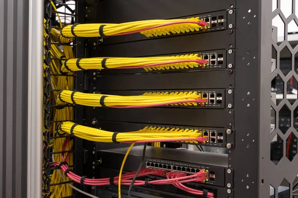 Close up on neat and tidy patched network cables, RJ45, connected to the switches and routers mounted on the rack in data centre, networking