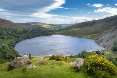 Lough Tay 'in manzarası, adı Guiness Gölü Wicklow Dağları, İrlanda' da demirli Viking uzun gemileri ve ahşap köyüyle