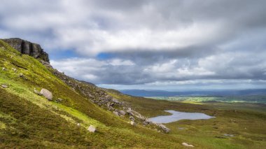 Kuzey İrlanda, Fermanagh bataklık ve sulak alanlarla çevrili küçük göle uzanan kayalık ve gürleme manzaralı Cuilcagh Dağı Parkı.