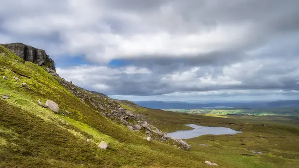 Kuzey İrlanda, Fermanagh bataklık ve sulak alanlarla çevrili küçük göle uzanan kayalık ve gürleme manzaralı Cuilcagh Dağı Parkı.