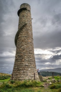 Anne ve kızı, İrlanda 'nın Wicklow Dağları' ndaki Lead Mines 'deki eski ve terk edilmiş taş bacanın dış sarmal merdivenlerinde duruyor.