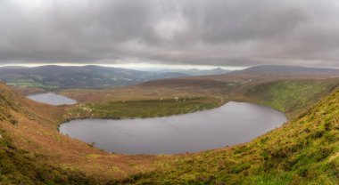 Üst ve alt göllerde panoramik manzara Lough Bray, Sugarloaf ve dağ sıraları. Wicklow Dağları, İrlanda 'da karamsar ve dramatik fırtına bulutları
