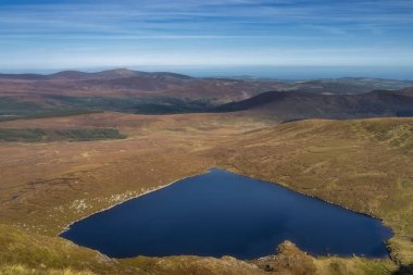 Tonelagee Dağı 'nın tepesinden, kalp şeklindeki göl, Lough Ouler, mavi gökyüzünü yansıtıyor. Wicklow Dağları 'nda yürüyüş, İrlanda