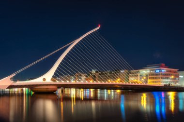Dublin, İrlanda, 10 Ekim 2020 Güzel arp Samuel Beckett köprüsü şeklindeydi. Şehir ışıkları Liffey Nehri 'ne, AIB Bank' a yansıyordu.