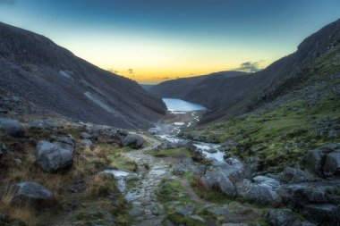 Taştan patika, Glendalough Gölü manzaralı patika, dere ve vadi. Gün batımında Wicklow Dağlarında yürüyüş, İrlanda