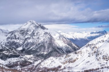 Panorama with a view on a beautiful mountain range with snowcapped mountain peaks, valley and forest, Montgenevre ski village, Alps, France clipart