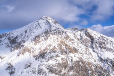 Yukarıda süzülen dramatik bulutlarla süslenmiş, gerçekten görkemli bir dağ zirvesinin nefes kesici manzarası, açık hava ve doğa meraklıları için mükemmel, Montgenevre kayak köyü, Alps, Fransa