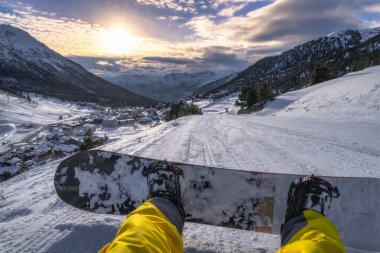Gün batımında heyecan verici bir snowboard macerası yaşayın. Karla kaplı dağların nefes kesici güzelliğinin ve etrafınızdaki sakin doğanın tadını çıkarın. Montgenevre kayak köyü, Alps, Fransa.