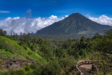 Explore the stunning landscape featuring a volcano, dense forests, and a dramatic sky, perfect for nature lovers and adventure seekers, East Java, Ijen Volcano, Indonesia clipart