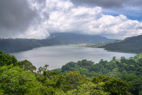 Потрясающий пейзаж с тихим озером среди пышных холмов, под живописным небом, идеально подходит для любителей природы и любителей активного отдыха, ищущих приключений, Бали, Индонезия