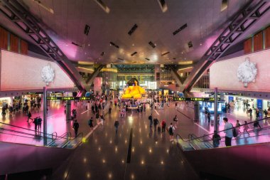 Doha, Katar, 27 Sep 2024 Hamad havaalanı terminalinde modern mimari, dinamik ışıklandırma ve dünyanın dört bir yanından gelecek maceraya hevesli gezginlerden oluşan canlı bir kalabalık yer alıyor.