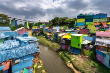 Malang, Java, Endonezya, 2 Ekim 2024 Nehir kenarındaki eşsiz bir sanatsal topluluğun canlı renklerini keşfedin, yemyeşil çimlerin ortasındaki boyalı evleri inanılmaz görsel bir deneyim için sergileyin.