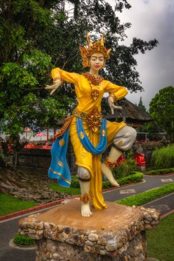 Bali, Indonesia, 4 Oct 2024 A striking statue of a traditional dancer in vibrant colors, showcasing cultural heritage in a garden that invites reflection and contemplation in Ulun Danu Beratan Temple clipart