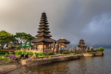 Bali, Indonesia, 4 Oct 2024 Experience the stunning view of a Balinese Ulun Danu Beratan Temple by a tranquil lake, surrounded by vibrant gardens and a moody sky, ideal for relaxation and sightseeing clipart