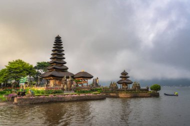 Bali, Endonezya, 4 Ekim 2024 Titrek bir Ulun Danu Beratan Tapınağı, ışıldayan suyla tünemiş ve hafif bulutlarla çerçevelenmiş, bu çarpıcı konumun sakin atmosferini artırır.