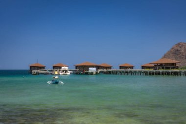 Quaint overwater bungalows perfectly nestled in pristine, crystalclear waters, surrounded by breathtaking natural beauty and a stunning scenic coastline that enchants, Labuan Bajo, Komodo, Indonesia clipart