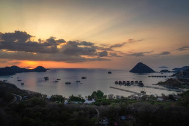 Göz kamaştırıcı ve büyüleyici bir günbatımı turuncu ve pembe renklerin canlı tonlarını sakin sularda boyar. Uzak adalar doğanın nefes kesici güzelliğini güçlendirir. Labuan Bajo, Komodo, Endonezya
