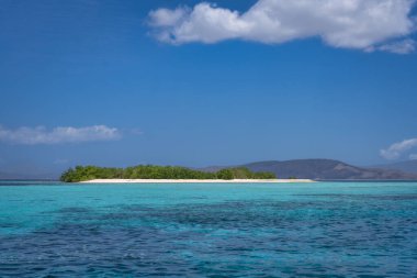 Kumlu plajı, yemyeşil yeşilliği, berrak turkuvaz suları ve rahatlamak ve doğal güzellikleri keşfetmek için ideal mavi gökyüzü olan sakin bir tropikal ada hayal edin. Komodo, Endonezya.